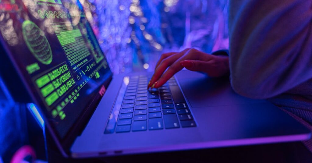 Close-up of hands typing on a laptop displaying cybersecurity graphics, illuminated by purple light.
